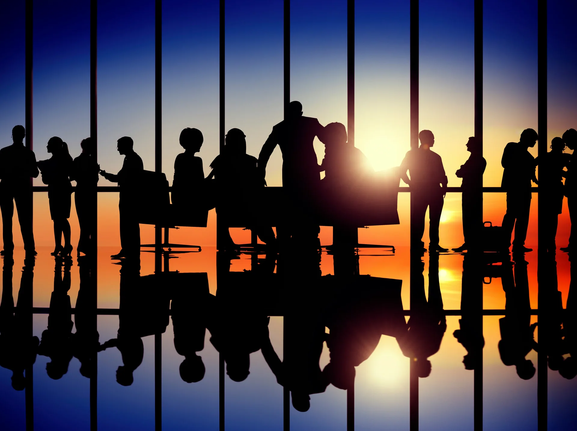 Businesspeople silhouetted against floor-to-ceiling windows