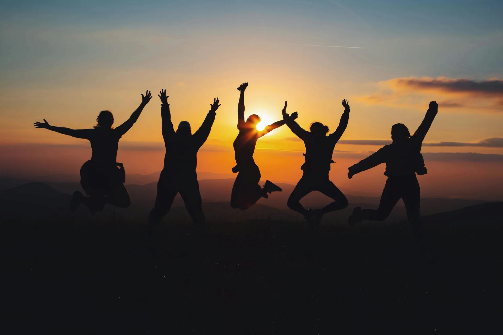Silhouettes of people jumping at sunset